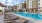 a chair and a pool in a courtyard with buildings in the background